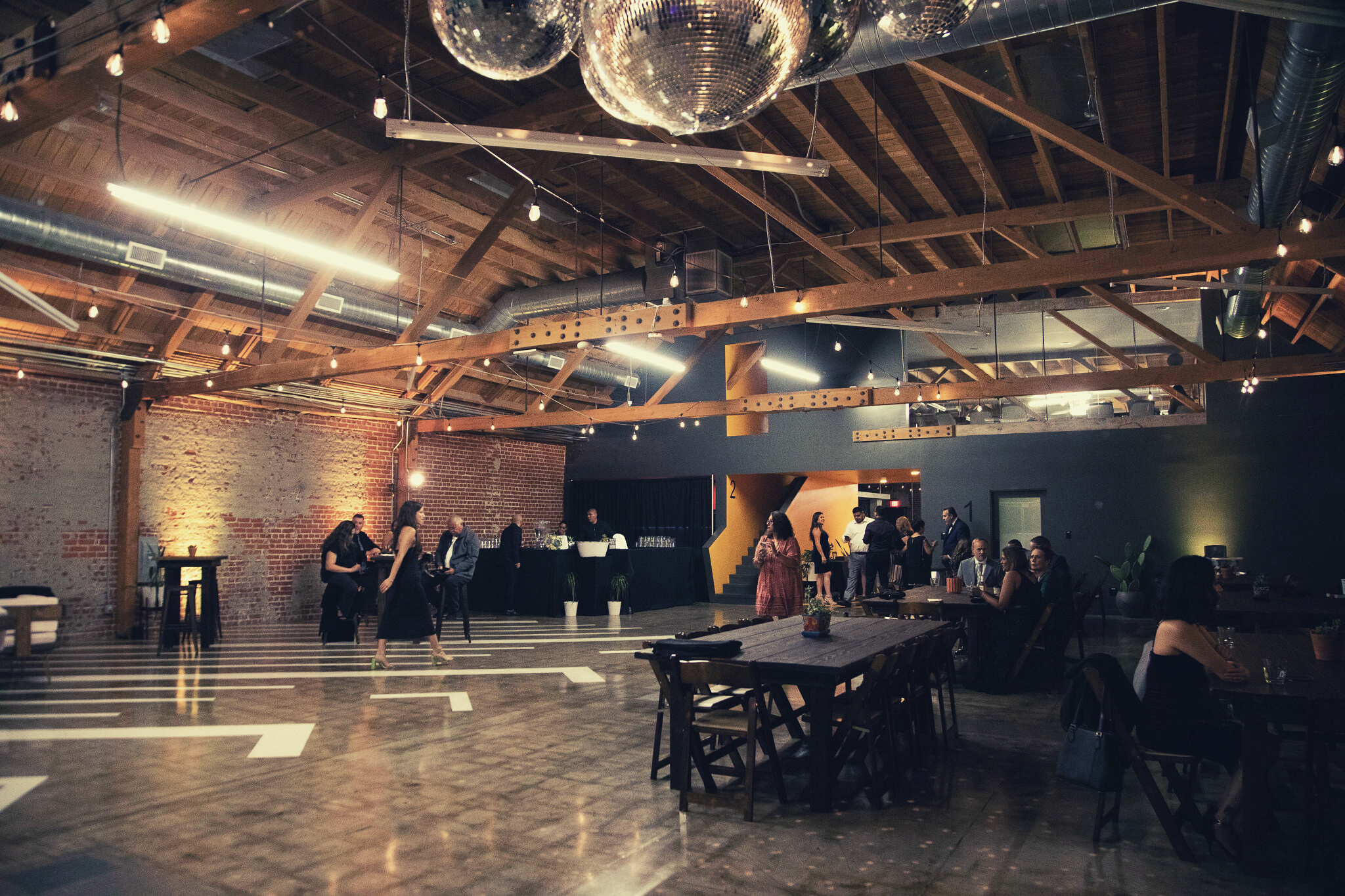 MG Studio Wedding Event Space Downtown Los Angeles Renovated Warehouse Exposed Brick Wood Beams Concrete Modern Industrial Chic - Evening Lighting Ambient Guests